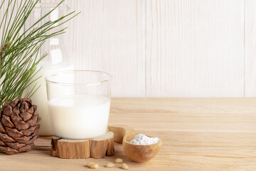 Organic milk replacer - cedar milk in glass, flour in wooden spoon for its cooking on wooden table.