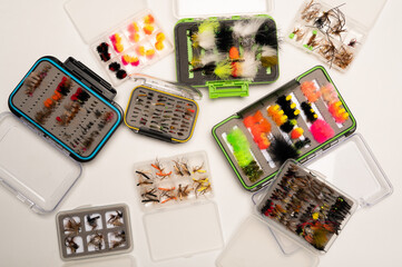 Various fishing flies in fly boxes looking down from above on a white background