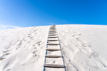 Ladder leading up to a sand dune with blue sky