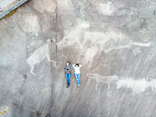 A couple of young people are studying the primitive White Sea petroglyphs