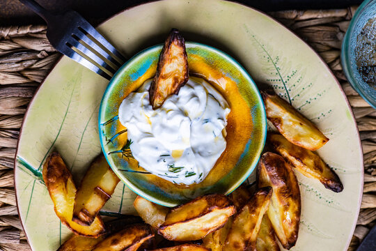 Overhead View Of Baked Potato Wedges With Sour Cream, Garlic And Dill Dip