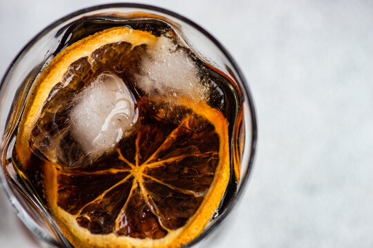 Overhead view of a cola drink with ice cubes and slices of orange