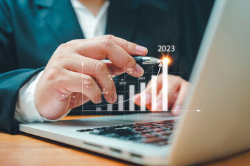 Businessman using computer analyzes profitability of working companies with digital augmented reality graphics,positive indicators in 2023,business calculates financial data for long-term investments.