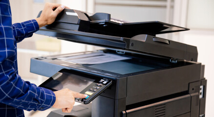 Businessmen press button on the panel for using photocopier or printer for printout and scanning document paper at office.