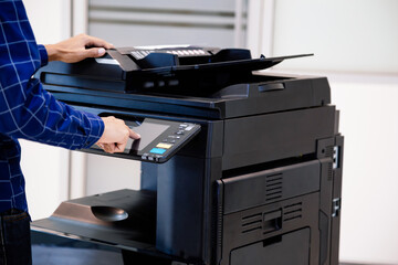 Businessmen press button on the panel for using photocopier or printer for printout and scanning...
