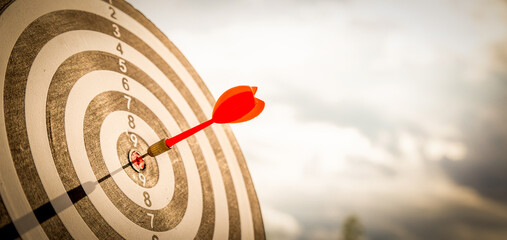 Close up shot red darts arrows in the target  of dartboard center on dark blue sky background....