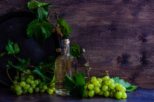 Bottle of Georgian chacha brandy on a table with a bunch of green grapes
