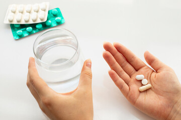 Healthcare and medical concept. Person holding pill in one hand and glass of water in the another hand. Flat lay.