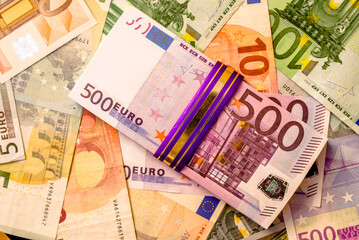 A pack of European currency lies on the background of the Euro