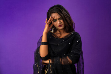 A young beautiful woman has stress or has the pain of a headache on a purple background.