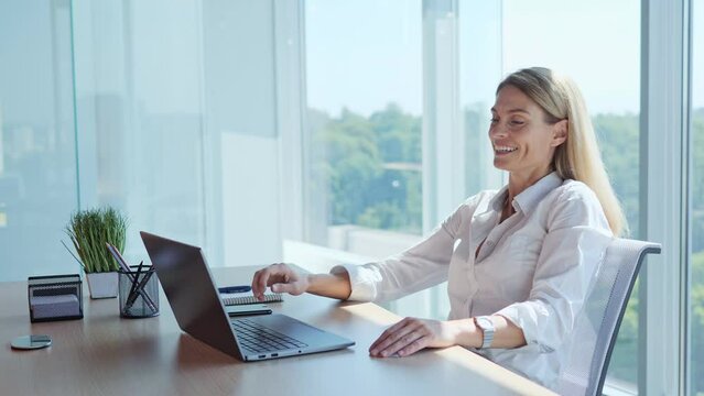 Smiling satisfied adult business woman finished work on laptop stretching sitting at workplace desk. Happy relaxed businesswoman feeling stress relief after job well done gesturing with her hands.