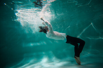 Beautiful underwater shooting, guy in white shirt and pants has fallen under the water and...