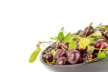 Several ripe sweet cherries in a black ceramic plate, close-up, isolated on a white background.