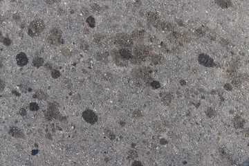 A road for vehicles covered with stains and pollution from oil and fuel of cars