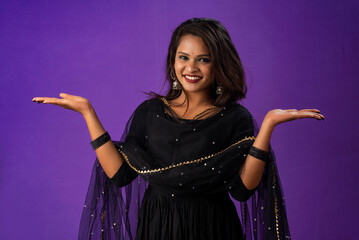 Portrait of a successful cheerful young girl holding and presenting something on hand with a happy smiling face.