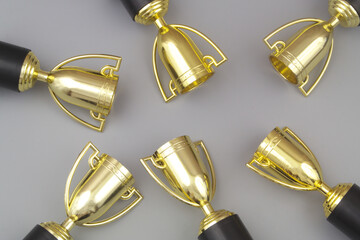 Many gold champion trophy cups on gray background