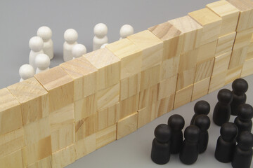 White and black people figures separated by high wall on gray background. People migration and...