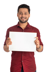 A happy young man holding and displaying a signboard or placard in his hands on a white background.