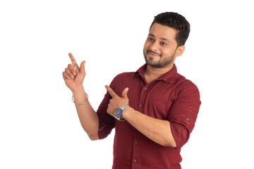 Portrait of a successful cheerful young man pointing and presenting something with hand or finger with a happy smiling face.