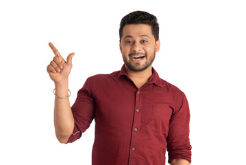 Naklejka premium Portrait of a successful cheerful young man pointing and presenting something with hand or finger with a happy smiling face.