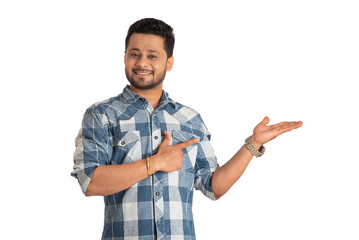 Portrait of a successful cheerful young man holding and presenting something on hand with a happy smiling face.