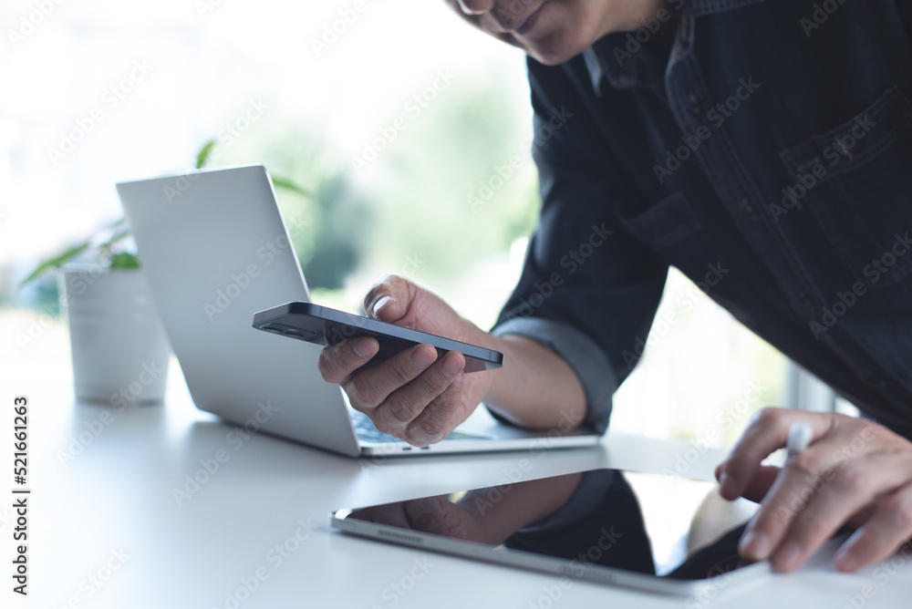 Poster asian business man, designer using mobile smart phone and working on laptop computer with digital ta