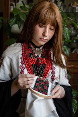 A girl embroiders a traditional Ukrainian vyshyvanka pattern - 521661877