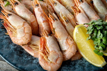Boiled shrimps on a wooden background, lemon and tomatoes. Macro