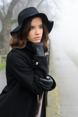 Fototapeta premium Beautiful woman in black clothes walking outdoors in a mist on autumn day