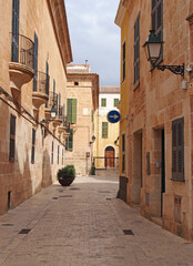 A quiet empty picturesque cobbled narrow street in ciutadella menorca with balconies and street lamps on colorful old houses