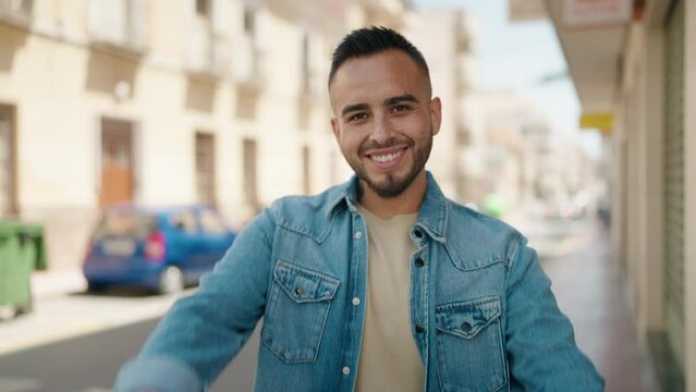 Young hispanic man smiling confident doing photo gesture with hands at street