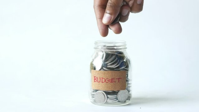 saving coins in a glass jar with budget text 