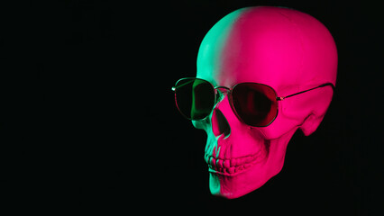 human skull wearing sunglasses with pink green neon light on a black background