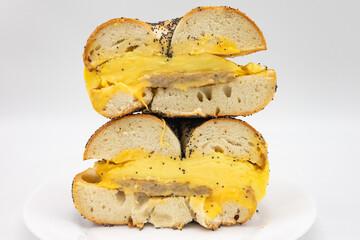 New York City Style Poppy Seed Bagel Cut in Half and Stacked and Filled with Eggs Cheese and Sausage