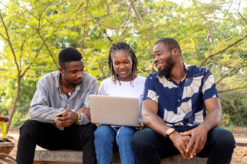 Group of learning millennial african american computer science students at university or college using laptop outside school campus