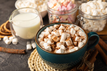 Cup of tasty cocoa drink and marshmallows in blue cup.Spices and marshmallows for winter drinks on black texture table.Winter hot drink.Hot chocolate with marshmallow and spices.Copy space.