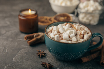 Cup of tasty cocoa drink and marshmallows in blue cup.Spices and marshmallows for winter drinks on black texture table.Winter hot drink.Hot chocolate with marshmallow and spices.Copy space.