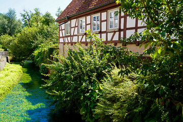 old timber-framed house on the river Blau (Blue) by the turquois pond Blautopf (Blue Pot) in Blaubeuren, Germany		