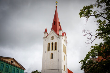 Fototapeta na wymiar Church tower with a gilded cross on top against a cloudy sky background