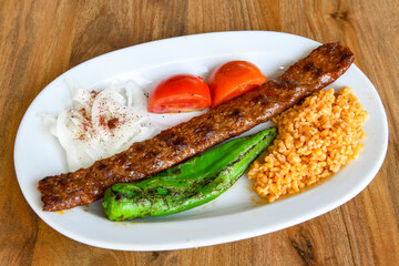 Grilled Turkish Adana, Urfa  Kebab with grilled vegetables, onion and rice on plate. Adana durum.