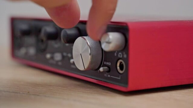 A close-up of a man turns the volume knob in a special device to make the music louder or quieter. Control panel on a sound amplifier.Add sound to red sound card
