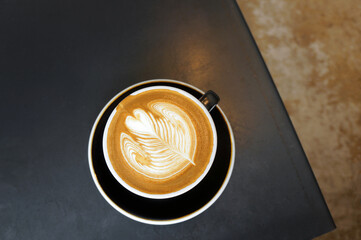 Top view of  hot coffee in cup with heart shape latte art on dark brown old wood table at caff food and drink concept.
