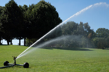 Mobile irrigation system water on a green lawn during a dry summer. Climate change