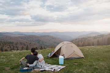 Rear on couple hugging and resting in mountains. On peak of mount, Beautiful view.