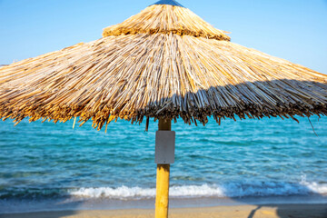 Straw beach umbrella close up. Sunny day at sea. Summer holiday in Greece