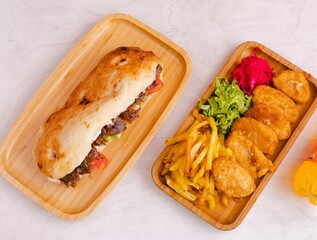 Beef doner kebab and chicken nuggets with vegetables on wooden tray top view 