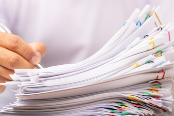 Man in a white shirt sign contract agreement documents in Stack of Group report papers.