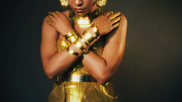 video with noise. Portrait Closeup fantasy african woman, hand in gold paint. Golden shiny skin dress bracelets necklace earrings arab style. Fashion model sexy girl. metallic makeup lips face cropped