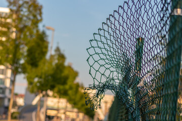 Green damaged wire-mesh fence is ruined after collision with car accident as crushed fence for car...