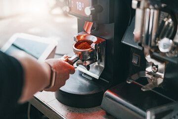 Barista grinds coffee beans pouring into a portafilter using coffee machine